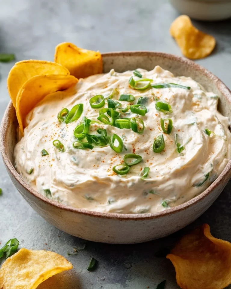 Bowl of easy cream cheese dip garnished with herbs and served with crackers