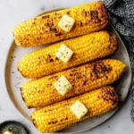Grilled corn on the cob, perfectly charred and served with butter and spices.