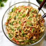 Plate of peanut noodles with chicken topped with peanuts and cilantro