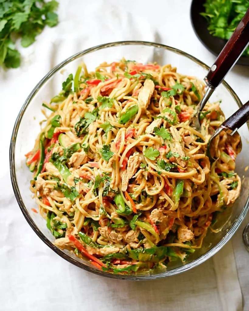 Plate of peanut noodles with chicken topped with peanuts and cilantro