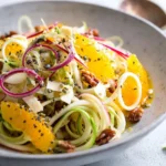 Spiralized apple salad topped with a zesty citrus dressing in a bowl.