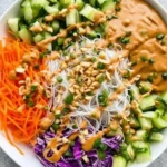 Delicious spring roll bowl topped with peanut sauce and fresh vegetables