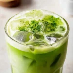 Delicious easy iced matcha latte in a glass with ice and matcha powder