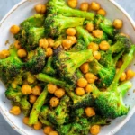 Delicious cheesy roasted broccoli and chickpeas dish garnished with herbs.