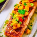 Plate of Chile Lime Salmon topped with fresh mango avocado salsa