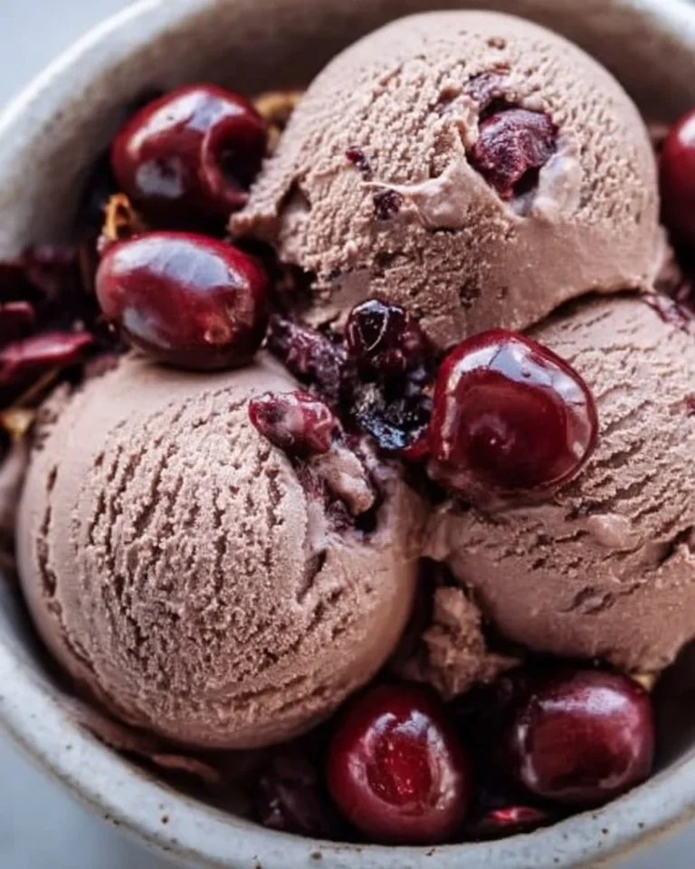 Delicious chocolate cherry ice cream in a waffle cone topped with cherries.