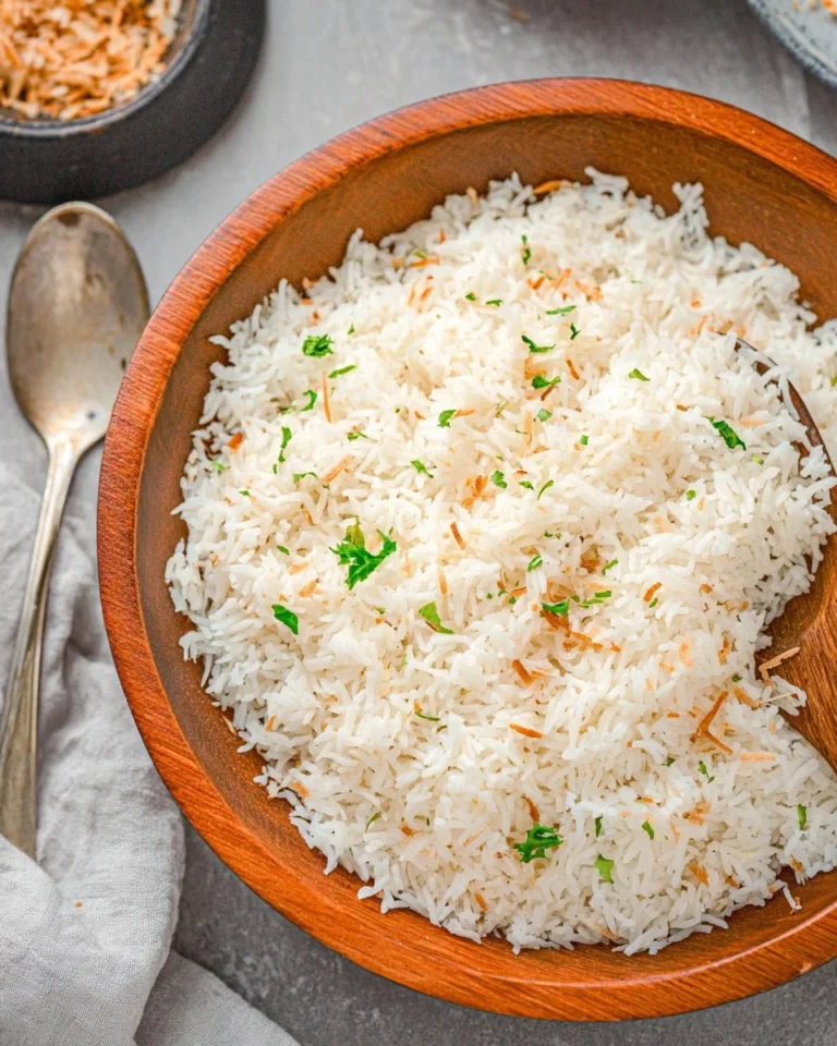 Bowl of Coconut Rice garnished with fresh herbs and served with tropical fruits