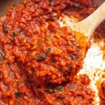 Homemade marinara sauce in a bowl with fresh basil and tomatoes