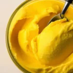 Delicious Ninja Creami mango sorbet in a bowl, served with fresh mango slices.