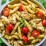 Pesto Parmesan Chicken served with pasta on a wooden table