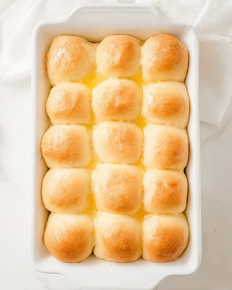 Freshly baked potato dinner rolls on a wooden table.