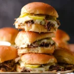 Pulled roast beef sliders served on a wooden platter with condiments