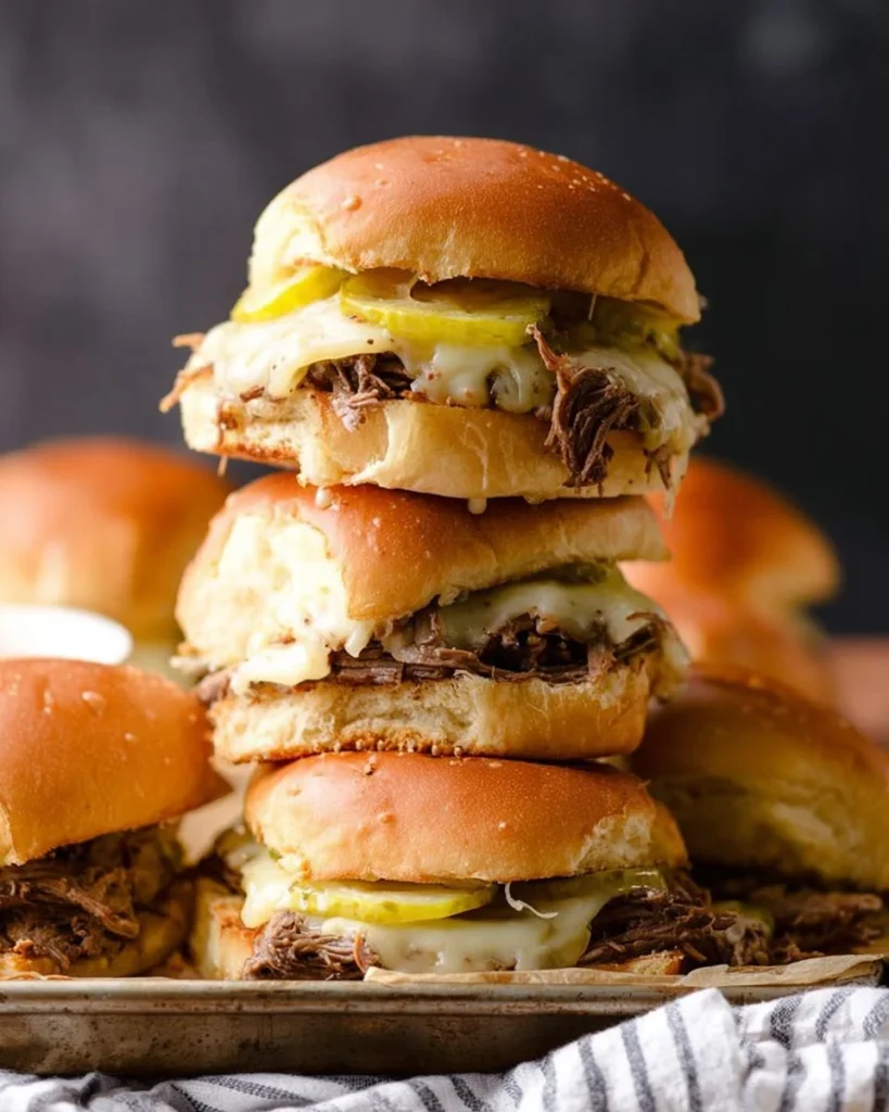 Pulled roast beef sliders served on a wooden platter with condiments