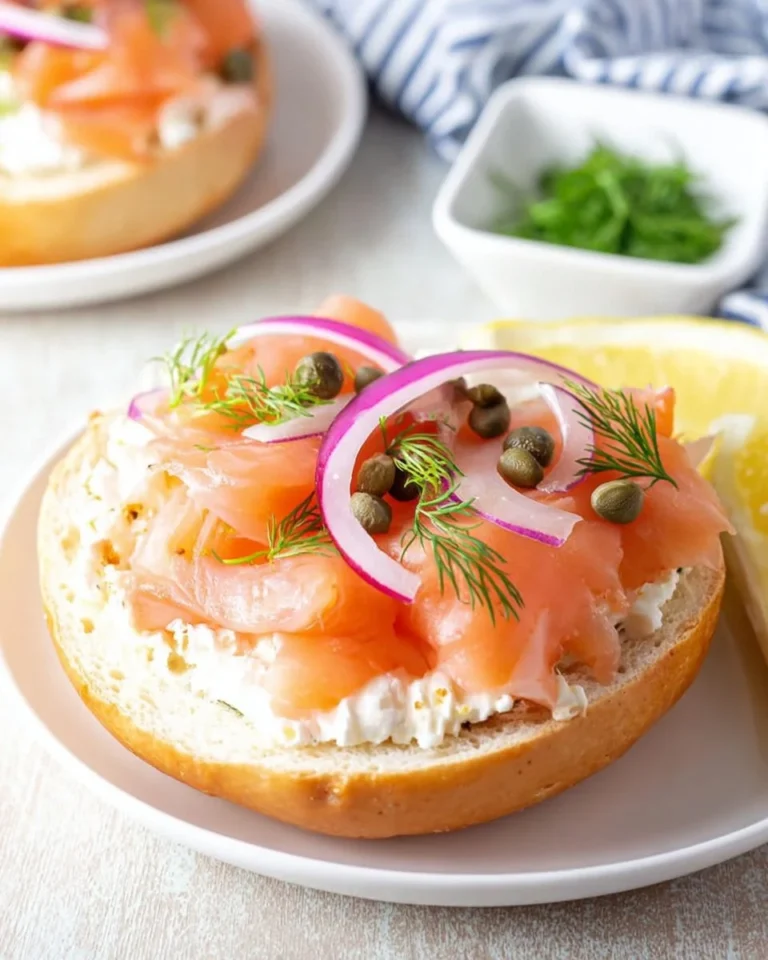 A gourmet smoked salmon bagel topped with cream cheese and fresh herbs.
