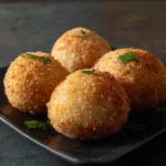 Baked Italian rice balls served on a white plate with marinara sauce.