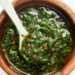 Fresh chimichurri sauce served in a bowl with herbs and spices