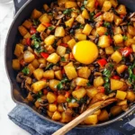 A hearty breakfast hash featuring potatoes, eggs, and colorful vegetables.
