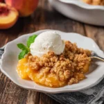 Fresh peach crumble topped with a golden brown crust served in a baking dish.