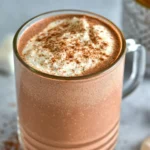 A steaming cup of high protein hot chocolate topped with whipped cream and cocoa