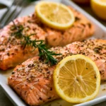 A plate of lemon pepper salmon garnished with herbs and lemon slices.