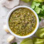 Roasted tomatillo salsa in a bowl with fresh ingredients