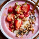 Delicious and colorful strawberry smoothie bowl topped with fresh fruits and seeds.