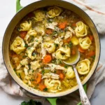 Bowl of Chicken Tortellini Soup garnished with herbs and vegetables