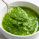 Fresh homemade cilantro sauce in a bowl with herbs and lime