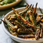 Crispy oven roasted okra served on a white plate with spices.