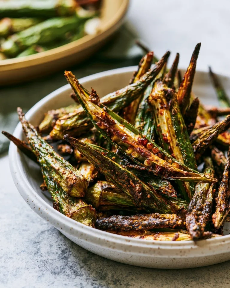Crispy oven roasted okra served on a white plate with spices.
