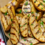 Grilled Salt and Vinegar Potatoes served on a plate, garnished with herbs.