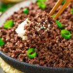 Plate of Korean ground beef with vegetables and rice garnished with sesame seeds