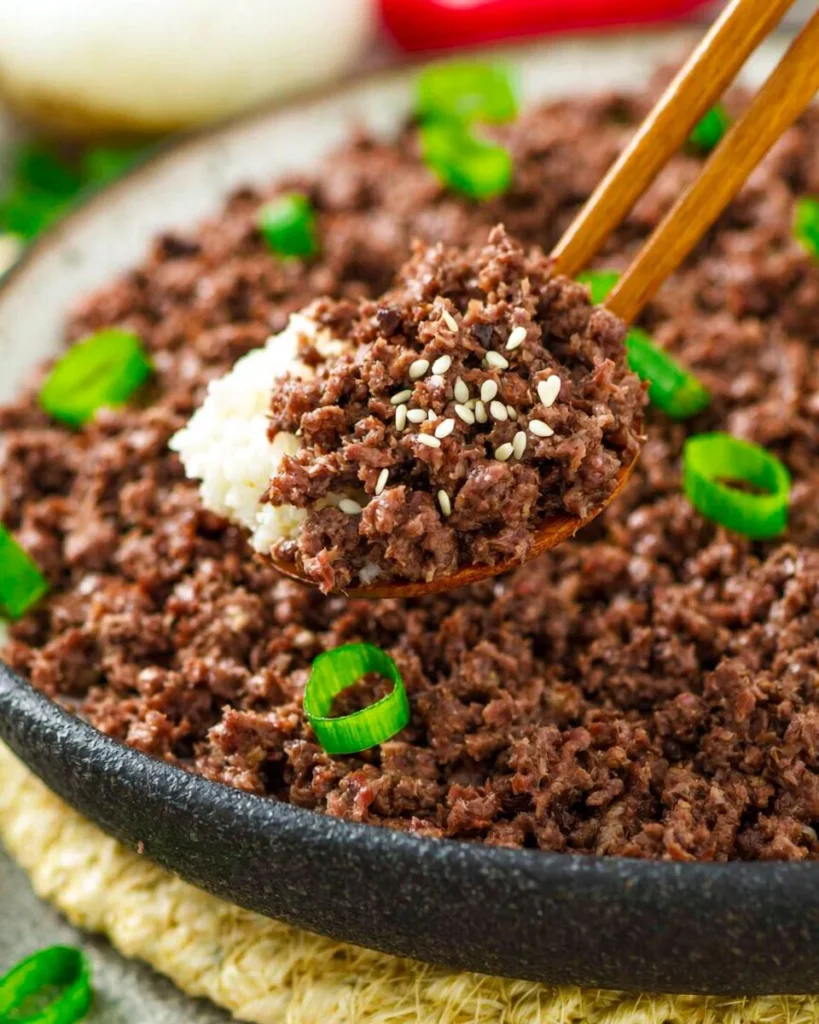 Plate of Korean ground beef with vegetables and rice garnished with sesame seeds