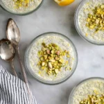 A bowl of creamy lemon chia pudding topped with fresh fruit and mint leaves.