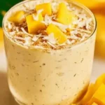 Healthy mango overnight oats topped with fresh mango slices and coconut flakes.