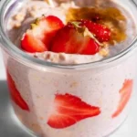 Bowl of strawberry overnight oats topped with fresh strawberries and nuts