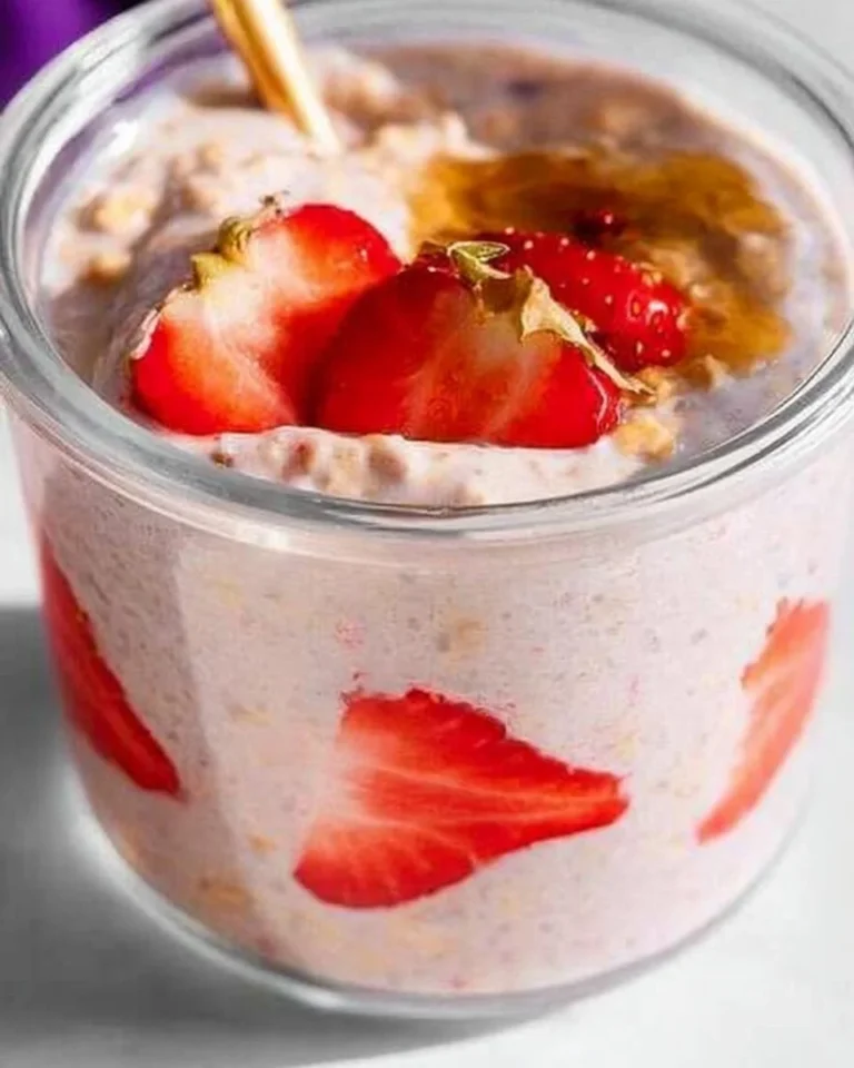 Bowl of strawberry overnight oats topped with fresh strawberries and nuts