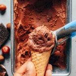 A bowl of Vegan Nutella Ice Cream topped with chopped hazelnuts and chocolate drizzle