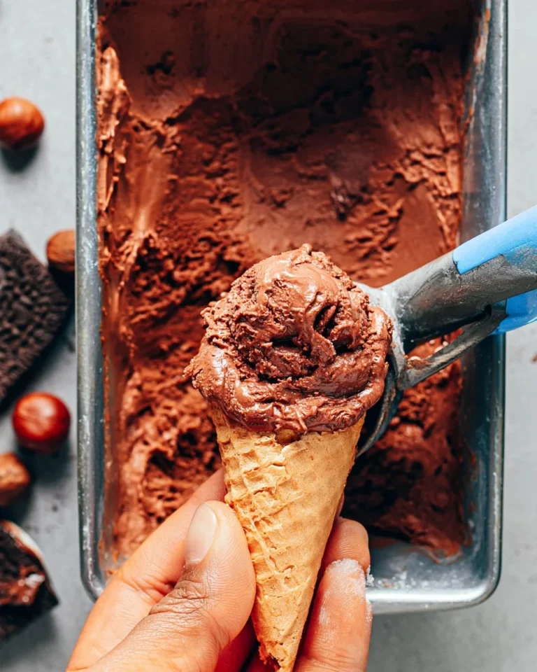 A bowl of Vegan Nutella Ice Cream topped with chopped hazelnuts and chocolate drizzle